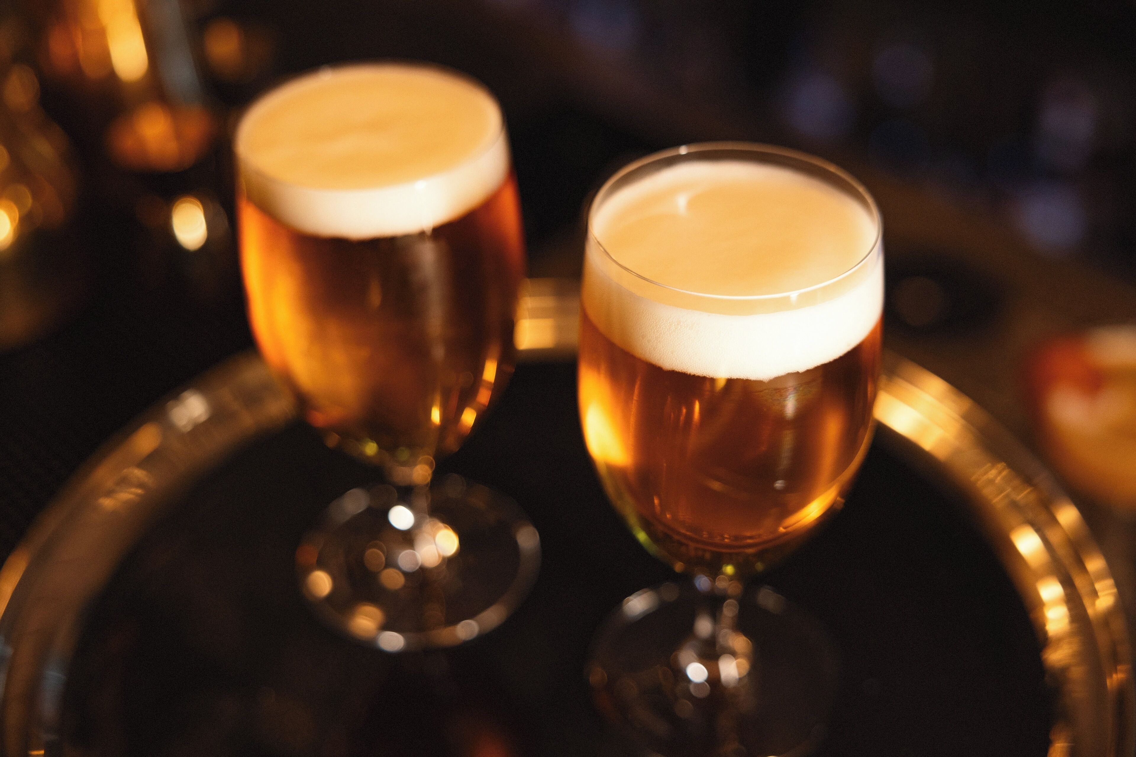 Two glasses of beer on a tray.