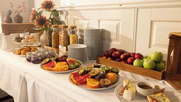 Una mesa de bufé con diversas frutas, quesos y pasteles.