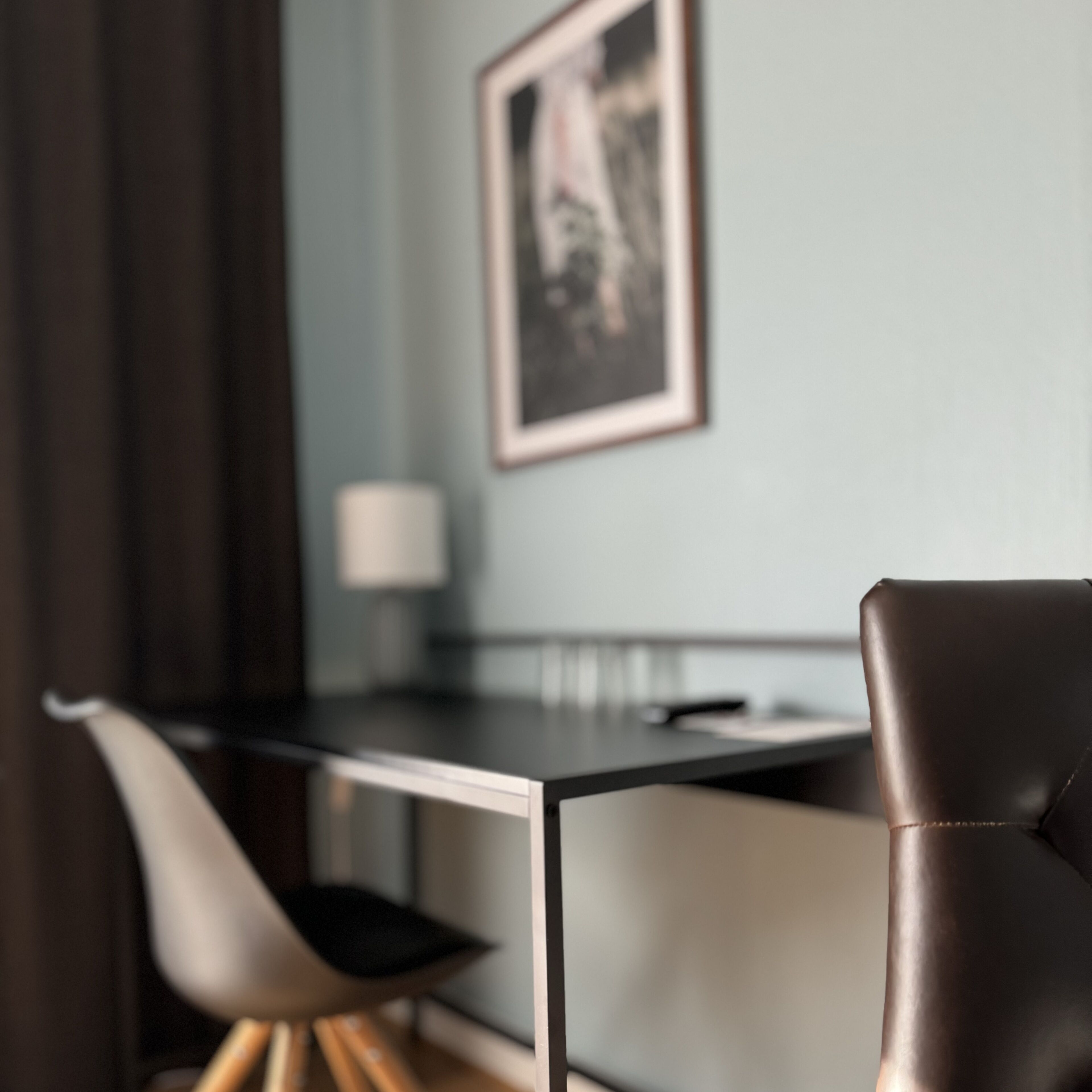 A modern dining area with a table, chairs, and a framed picture on the wall.