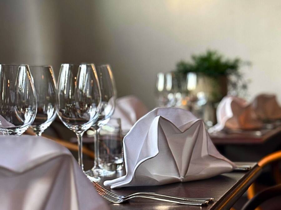 Une table à manger dressée avec des verres à vin transparents et des serviettes pliées.