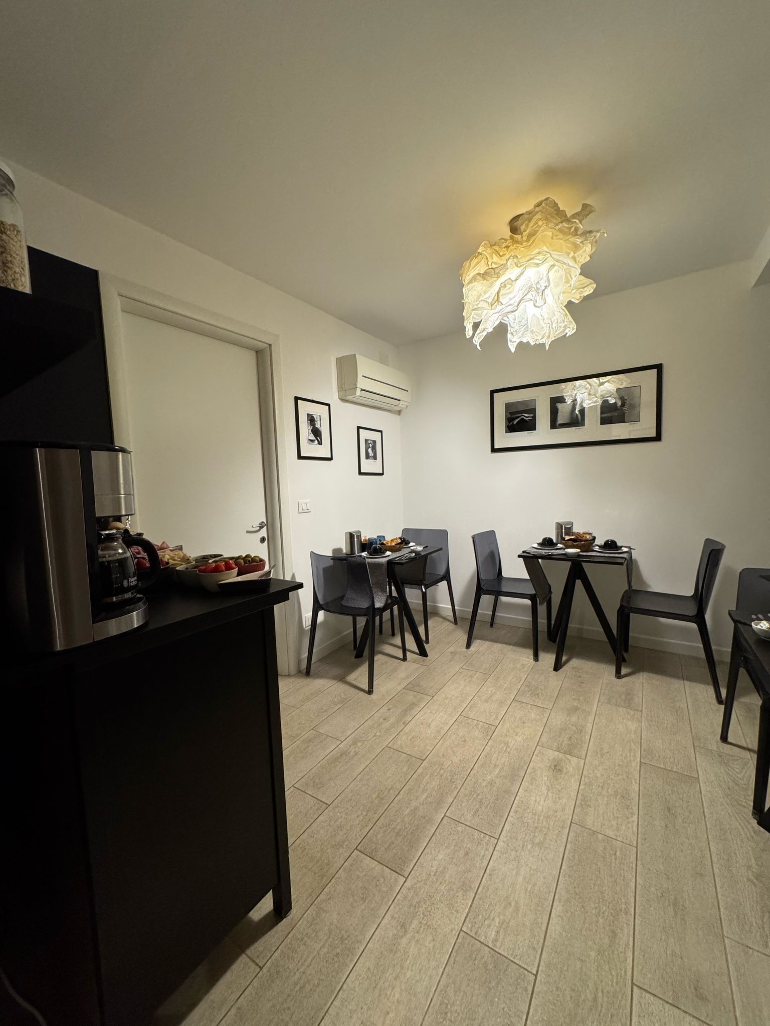 Une cuisine moderne dotée d’une cuisinière intégrée, d’un coin repas agrémenté d’un lustre et de tableaux encadrés accrochés au mur.