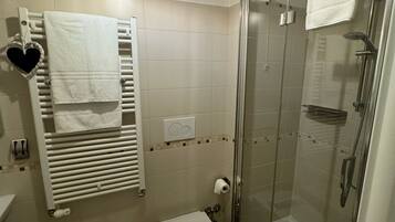 Un baño moderno con ducha de vidrio, un bidé, un inodoro y un perchero con un adorno con forma de corazón.