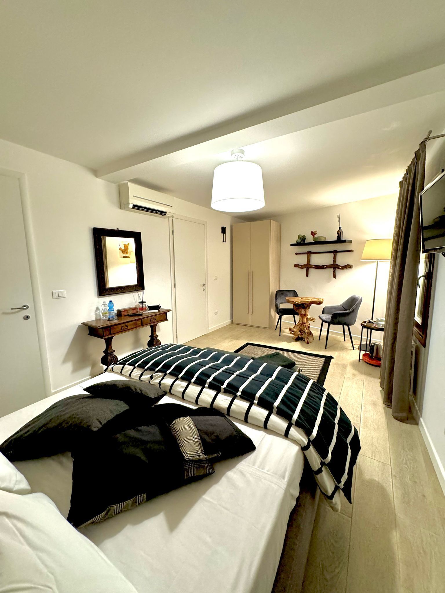 A hotel room with a bed, a desk, a chair, a TV, and a lamp.