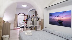 A modern bedroom with a large bed, a desk, and a bookshelf. - B&B Eraclio (Barletta)