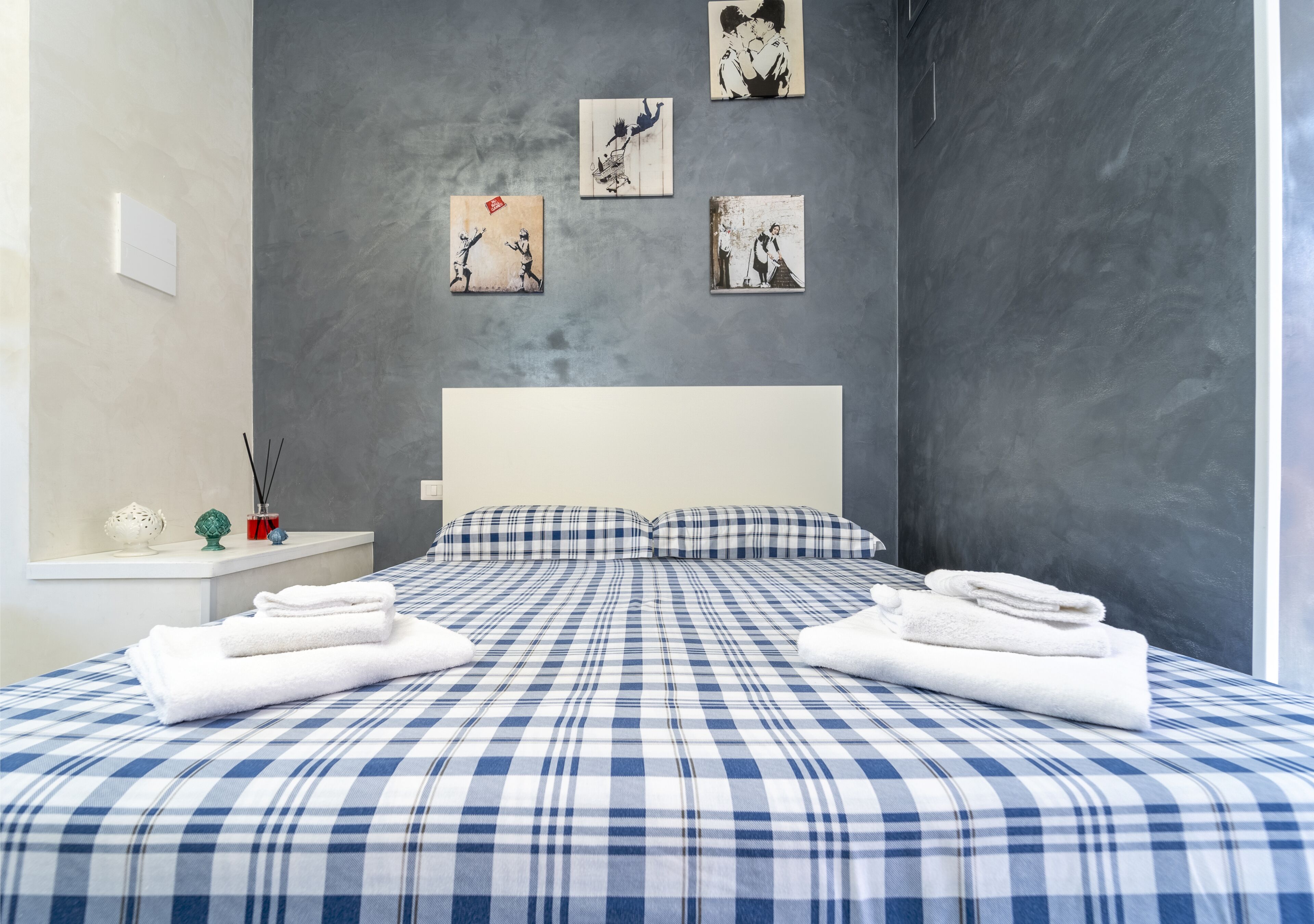 Un dormitorio moderno con una cama grande, cabecera blanca y obras de arte en las paredes.