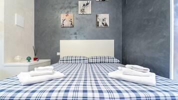Un dormitorio moderno con una cama grande, cabecera blanca y obras de arte en las paredes.