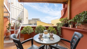 A small patio with a round table and chairs, potted plants, and a view of buildings in the background. - B&B Eraclio (Barletta)