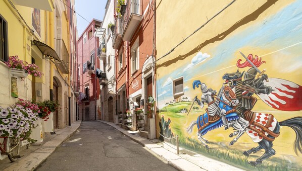 A narrow street with colorful buildings and a mural of a knight on horseback.
