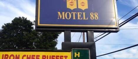 A motel sign with a logo, a sign for Iron Chef Buffet offering East Asian food, and a sign for Hibachi Sushi.