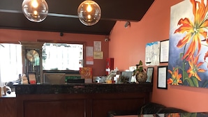 A bar area with a wooden counter, a piano, and a large floral painting on the wall. - Motel 88 (Oneonta)