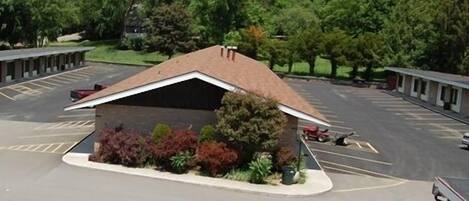 A motel with a central parking area, a covered outdoor seating area, and a row of individual rooms.
