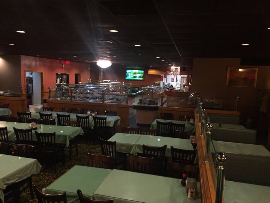Un restaurant doté de nombreuses tables et chaises, d’un bar et d’un écran de télévision.