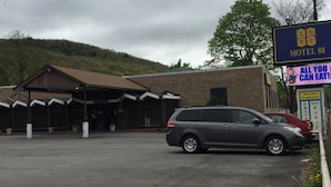 A motel with a sign reading "Motel 88" and a parking lot with a parked SUV. - Motel 88 (Oneonta)