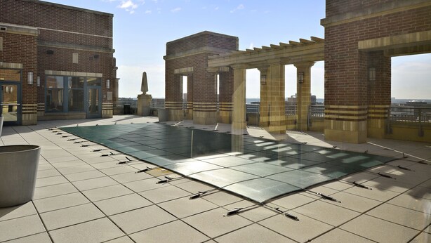 A rooftop terrace with tiled flooring, a pergola, and a view of the cityscape. - The Gramercy at Metropolitan Park (Arlington)