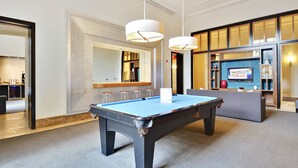 A pool table in a room with a bar area and a seating area. - The Gramercy at Metropolitan Park (Arlington)