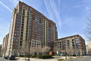 A multi-story residential building with a brick facade, multiple balconies, and a clear sky. - The Gramercy at Metropolitan Park (Arlington)