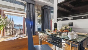 A dining area with a view of a historic building, a modern kitchen with a Samsung refrigerator, and a table set with breakfast items.