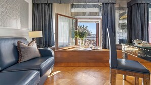 A modern living room with a leather sofa, a wooden coffee table, and a view of a busy street through a large window.
