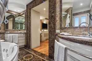 A luxurious bathroom with a large mirror, two sinks, a bathtub, and a vanity.