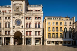 A historic building with a prominent clock tower, multiple balconies, and storefronts including 'GIOBAGNARA'.