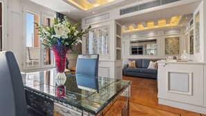A modern living room with a glass coffee table, a blue sofa, and a decorative vase with flowers.