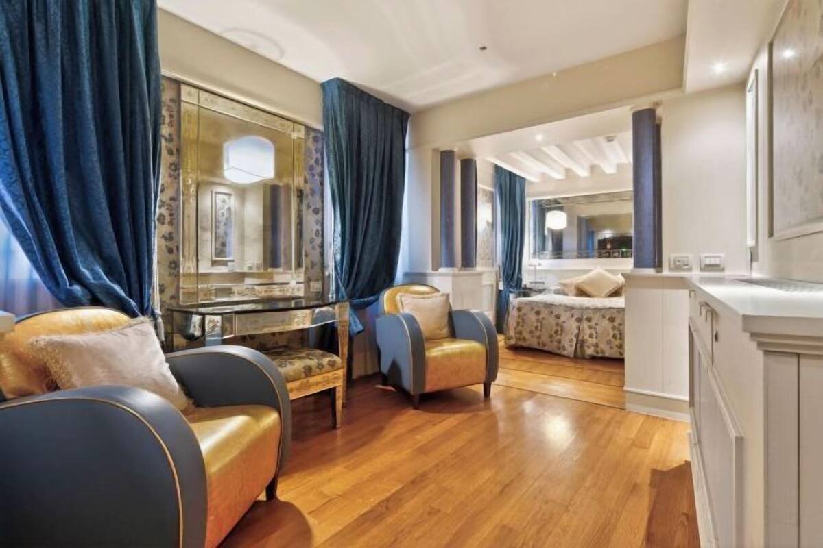 Une chambre d’hôtel spacieuse, dotée d’un grand miroir, d’une coiffeuse avec miroir, d’un canapé, d’un fauteuil et d’un lit.