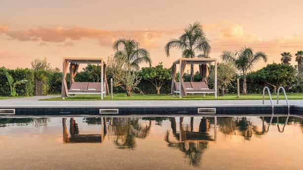 Un espace aménagé au bord de la piscine, avec deux chaises longues et une vue dégagée sur la piscine.