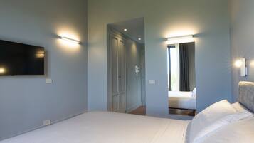 Un dormitorio con cama, televisor de pantalla plana montado en la pared y un espejo que refleja parte de la habitación.