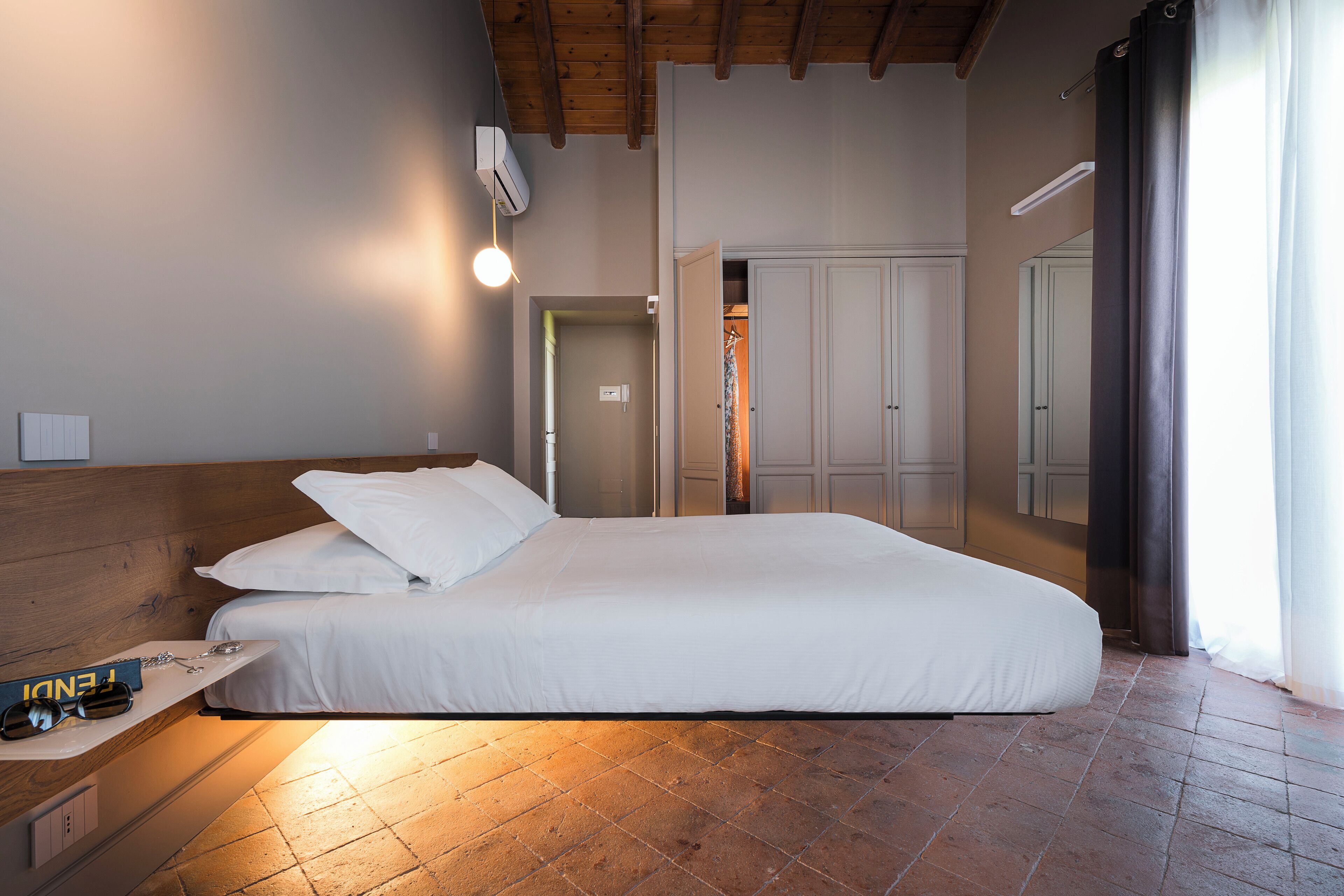 A bedroom with a large bed, wooden headboard, a bedside table with a lamp, and a wardrobe.