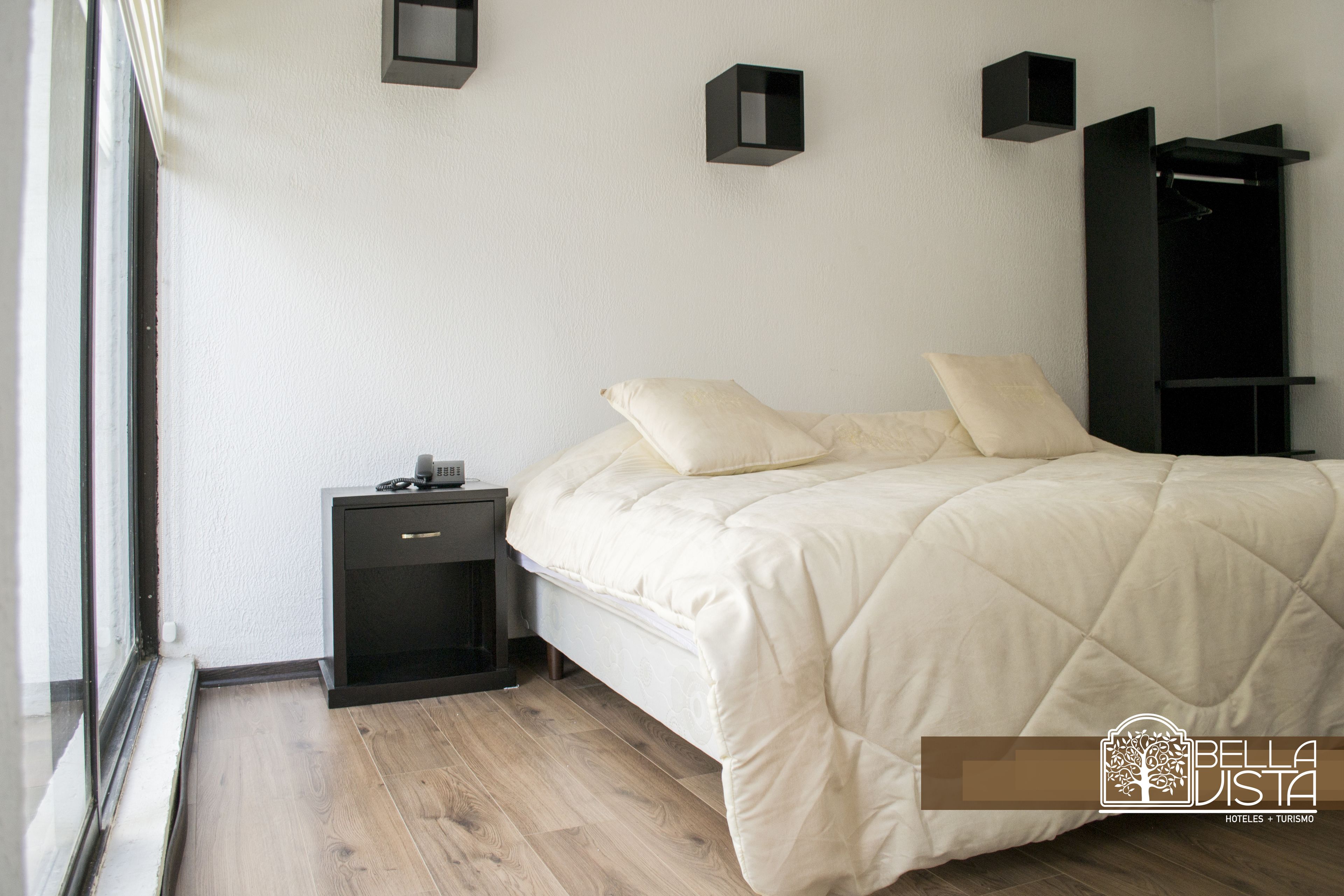 A bedroom with a bed, bedside tables, a wardrobe, and a window.