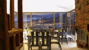 Un restaurante con vistas panorámicas de la ciudad, mobiliario de madera y una chimenea de ladrillo.
