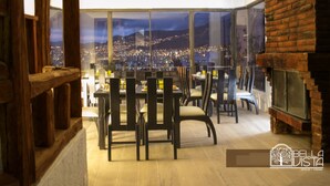 Un comedor con vistas a la ciudad, muebles de madera y una pared de ladrillo.