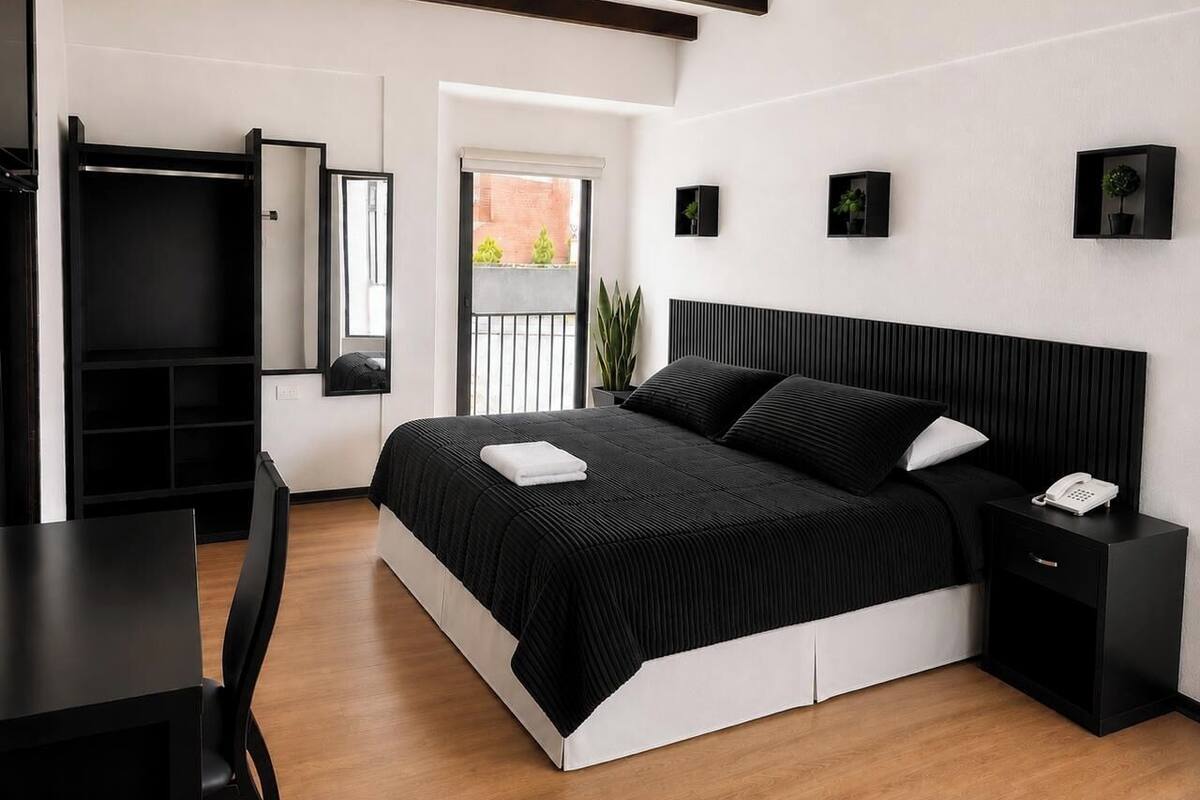 A modern bedroom with a large bed, bedside tables, a desk, and a wardrobe.