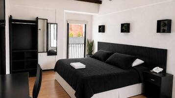 A modern bedroom with a large bed, bedside tables, a desk, and a wardrobe.