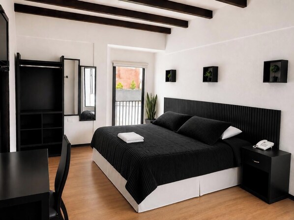 A modern bedroom with a large bed, bedside tables, a desk, and a wardrobe.