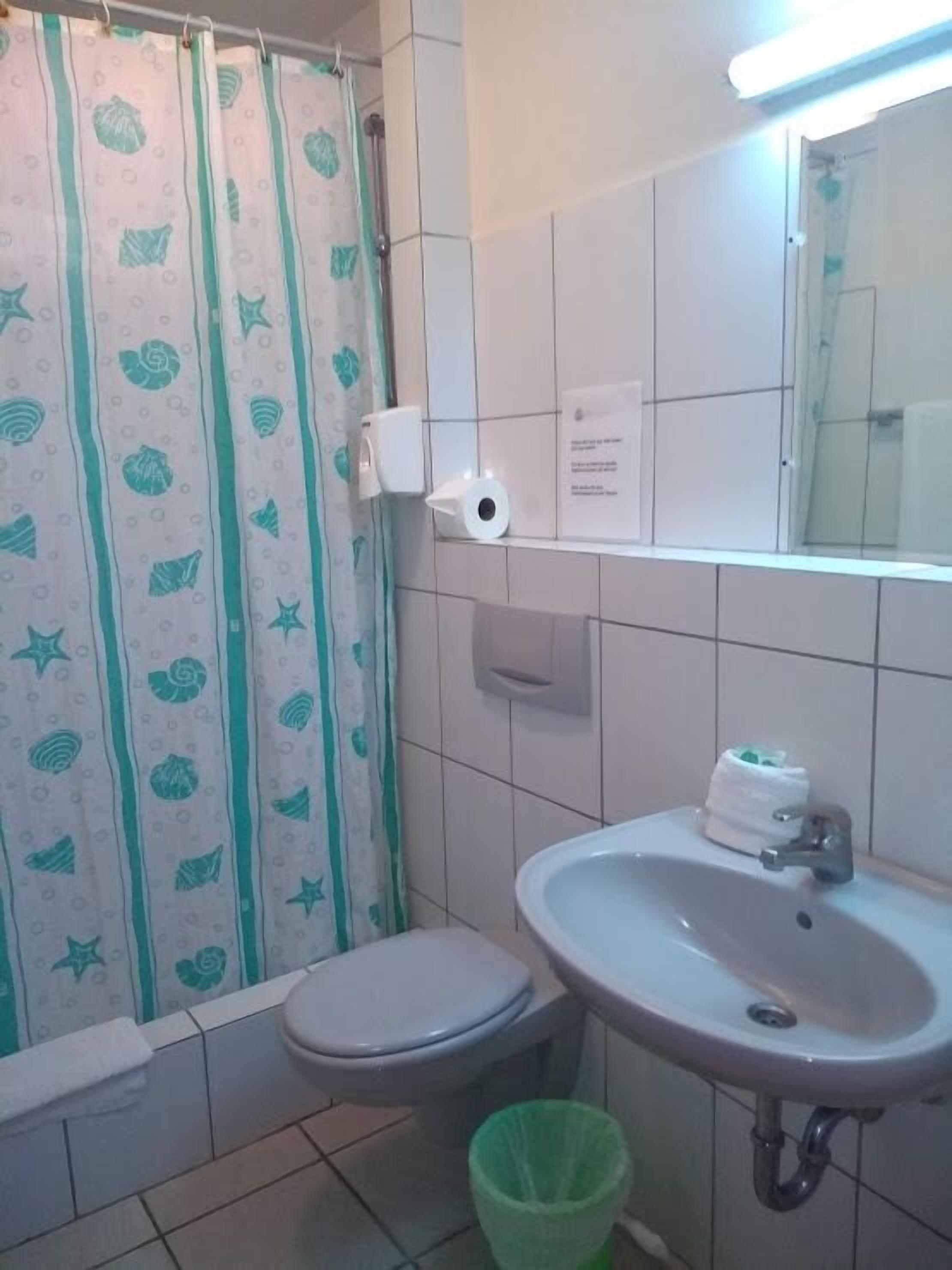 Une salle de bain équipée de toilettes, d’un lavabo et d’un rideau de douche.