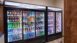 A self-serve beverage and frozen food vending area with multiple beverage options and frozen food items.