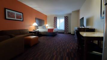 A hotel room with a sofa, a bed, a desk, and a TV.
