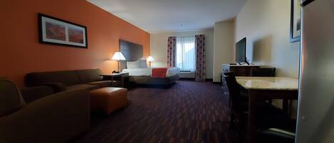 A hotel room with a sofa, a bed, a desk, and a TV.