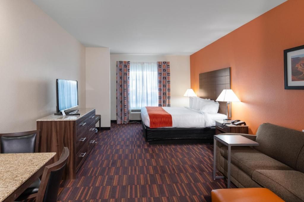 Une chambre d’hôtel équipée d’un lit, d’un bureau, d’une chaise, d’une télévision et d’un canapé.
