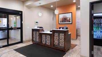 A reception area with a counter, a framed picture on the wall, and a refrigerator stocked with beverages.