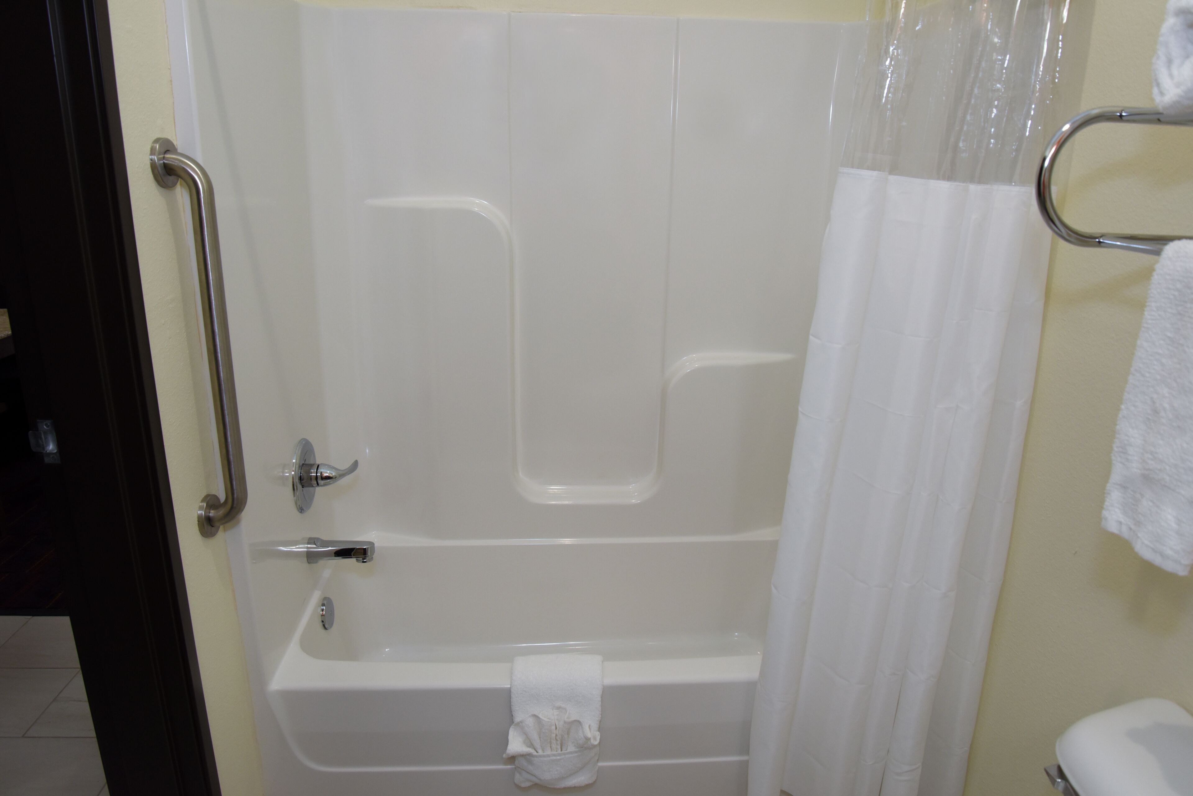 Een badkamer met een bad, douchegordijn, handdoekhouder en toilet.