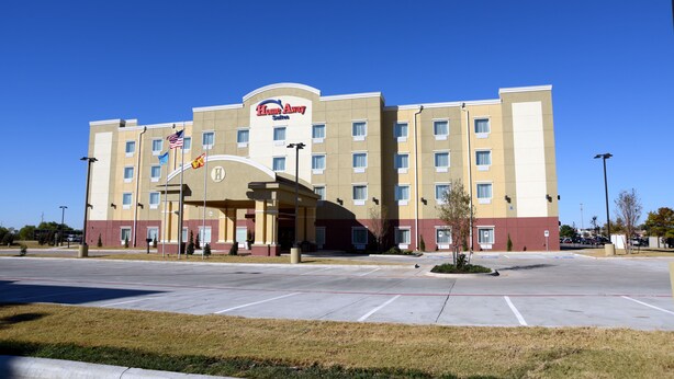 A hotel with a central entrance, multiple floors, and a parking lot.