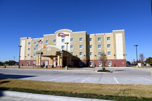 A hotel with a central entrance, multiple floors, and a parking lot. - Home Away Suites (Enid)