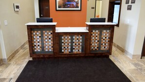 A reception desk with a check-in counter, a framed artwork above, and a tiled floor.