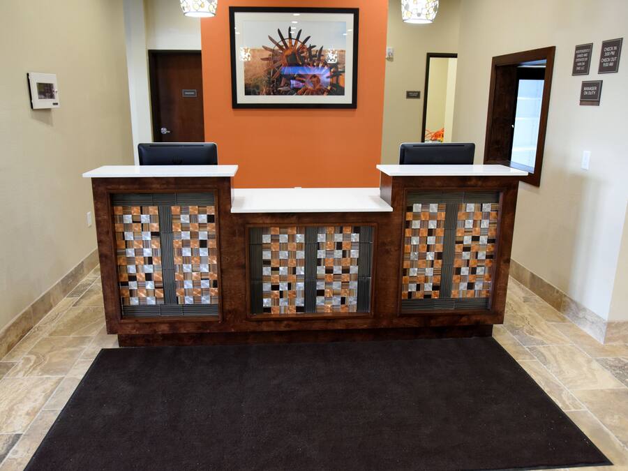 A reception desk with a check-in counter, a framed artwork above, and a tiled floor.