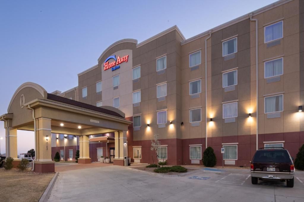 A hotel with a central entrance, multiple floors, and a parking lot.