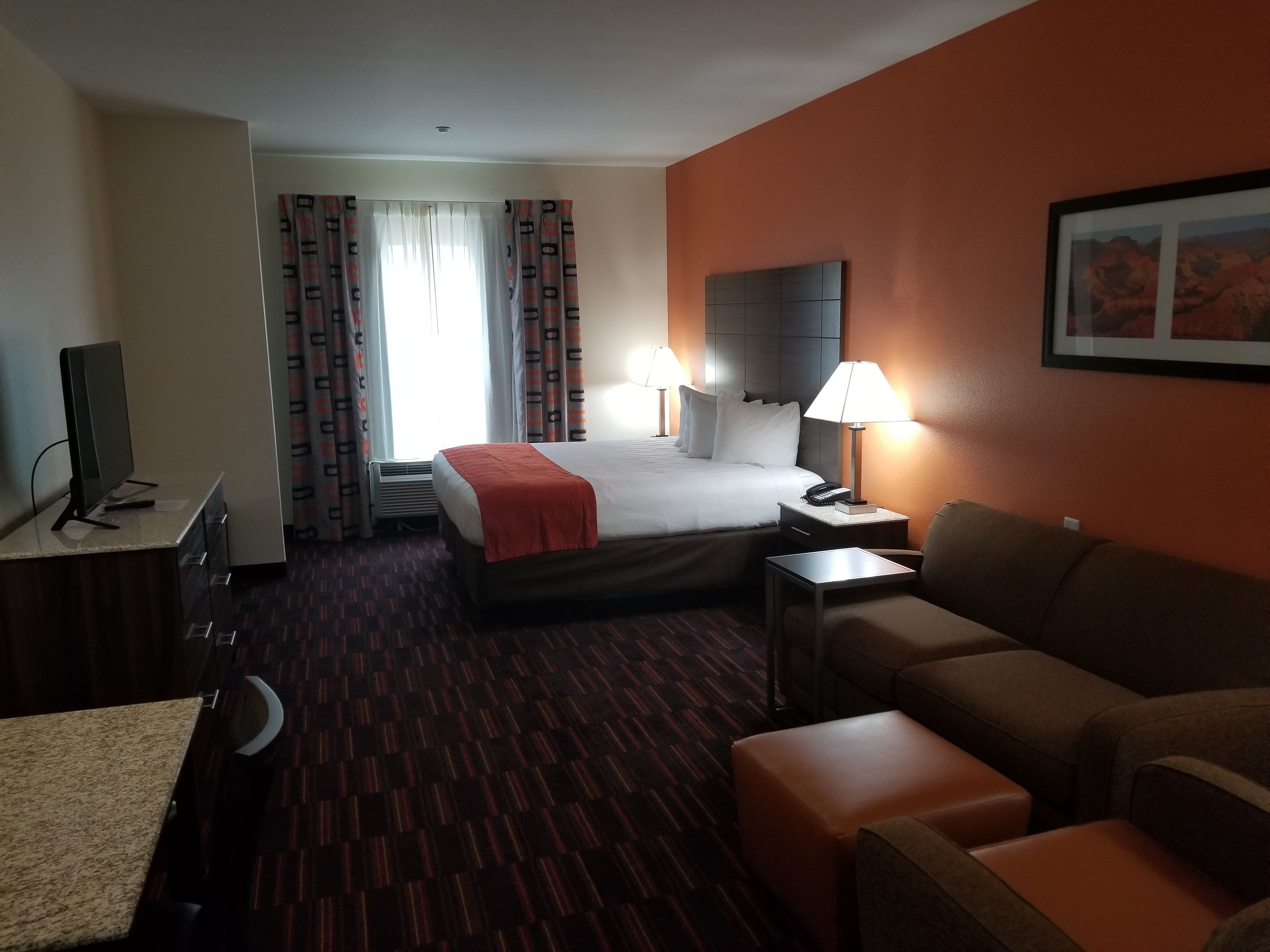 Una habitación de hotel con cama, escritorio, silla, sofá y televisión.