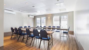 Una sala de conferencias con una mesa larga y sillas, ventanas amplias e iluminación empotrada en el techo.