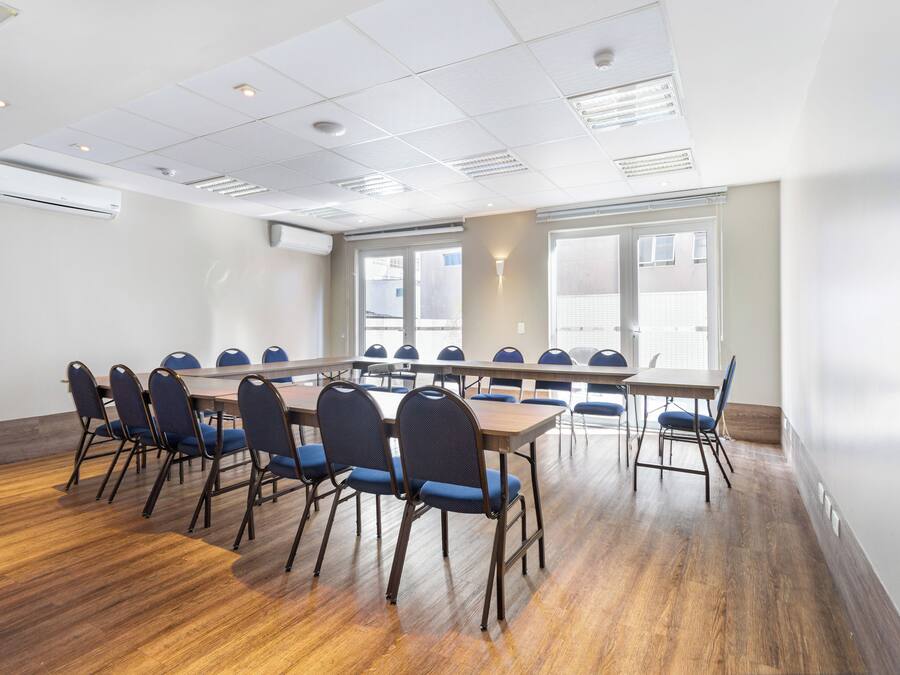 Una sala de conferencias con una mesa larga y sillas, ventanas amplias e iluminación empotrada en el techo.